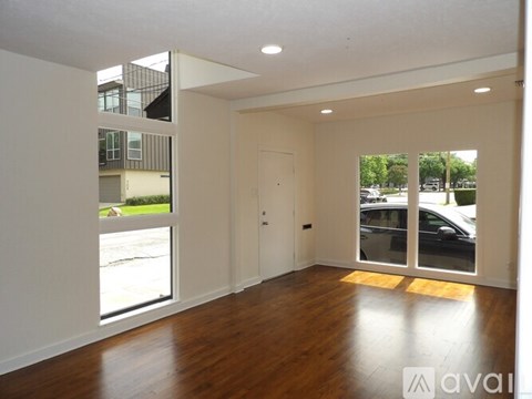 A spacious room with wooden floors and large windows.