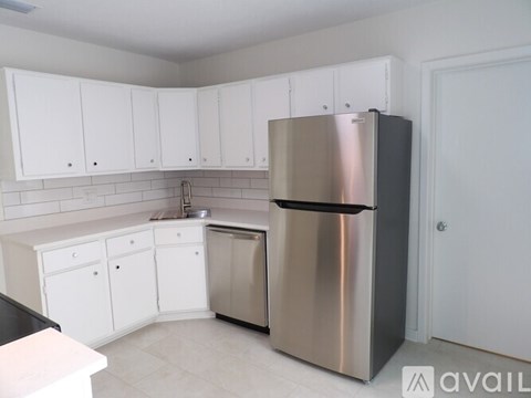 A kitchen with white cabinets and a stainless steel refrigerator.