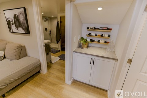 A living room with a couch, a cabinet with bottles on it, and a painting on the wall.