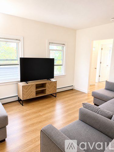 A living room with a grey sofa and a wooden tv stand.
