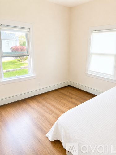 A bedroom with a bed and two windows.