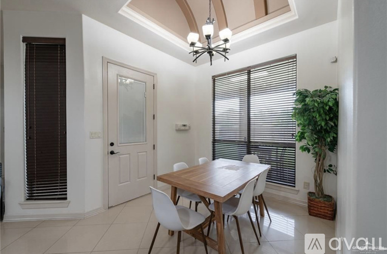 A dining room with a wooden table and white chairs.