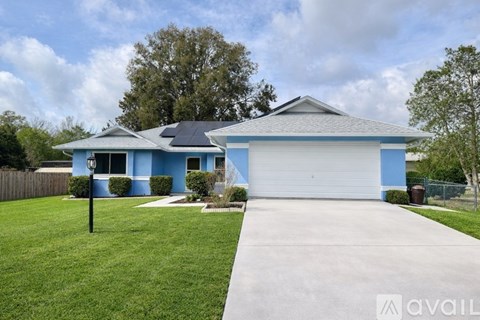 A blue house with a white garage door and a driveway leading to it.