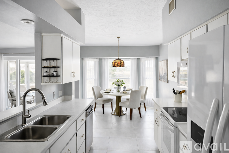 A modern kitchen with white cabinets and a dining table set for two.