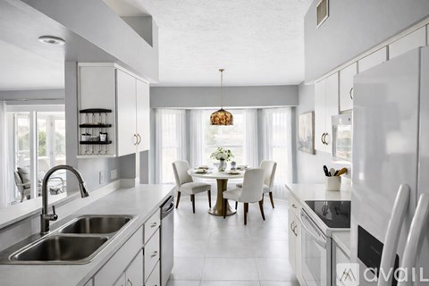 A modern kitchen with white cabinets and a dining table set for two.