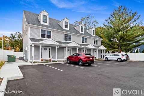 A red car is parked in front of a two-story house.