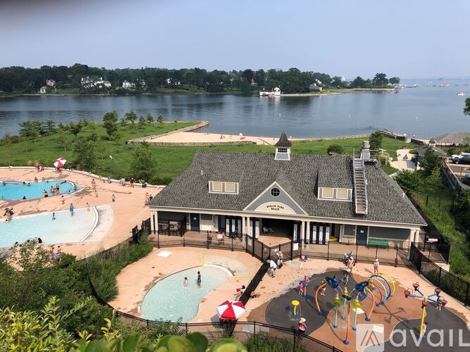 A large outdoor swimming pool with a water slide and a building with a balcony overlooking the pool.