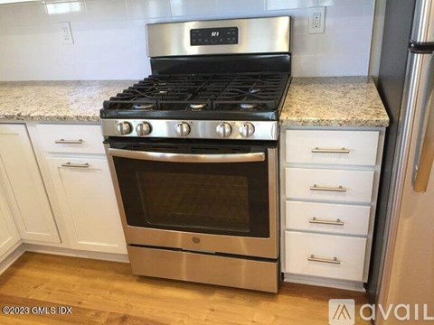 A modern kitchen with a stainless steel oven and white cabinets.