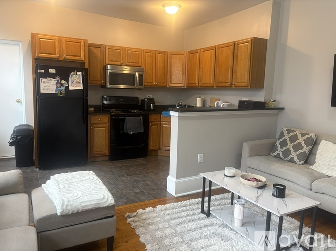 A black fridge with a white towel on a grey sofa.
