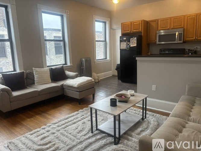 A modern living room with a grey sofa, a black fridge, and a wooden coffee table.