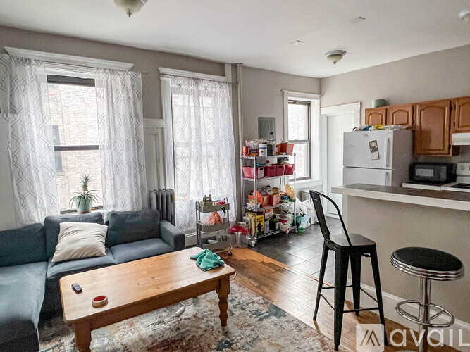 A living room with a grey couch, a wooden coffee table, and a kitchen area in the background.