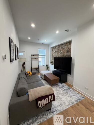 A living room with a grey couch and a brick wall.