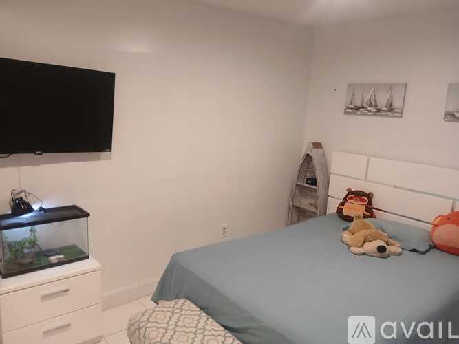 A bedroom with a bed, a fish tank, and a teddy bear.
