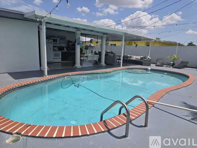 A pool with a red brick border and a metal ladder.