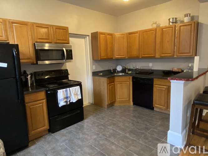 A kitchen with wooden cabinets and black appliances.