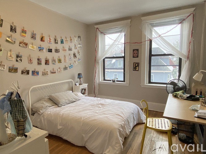 A bedroom with a bed, desk, and pictures on the wall.