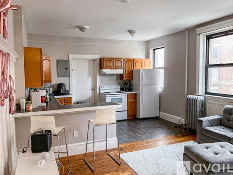 A kitchen with a refrigerator, stove, and bar stools.
