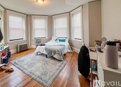 A bedroom with a large bed and a rug on the floor.