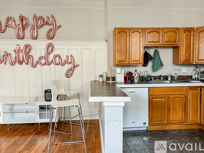 A kitchen with a birthday sign on the wall and a white chair in front of it.