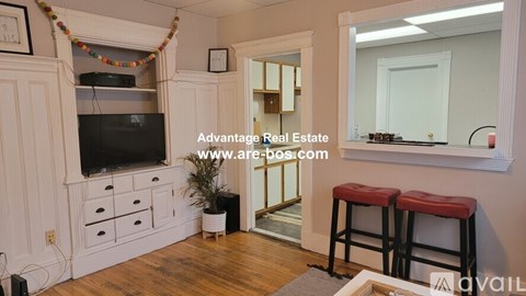 A living room with a television, bar stools, and a mirror.