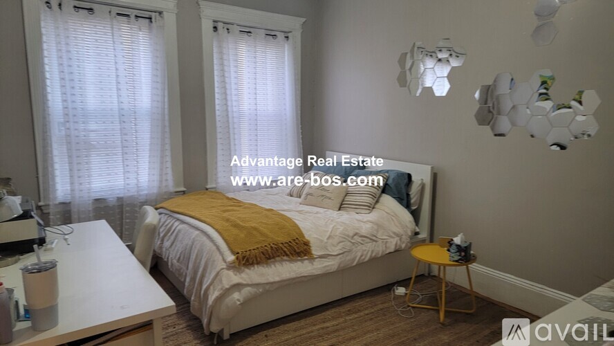 A bedroom with a bed, a table, and a lamp.