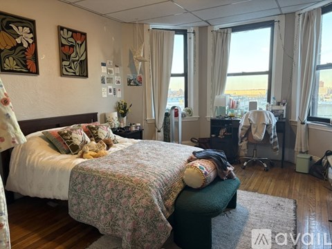 A bedroom with a large bed and a window overlooking the city.