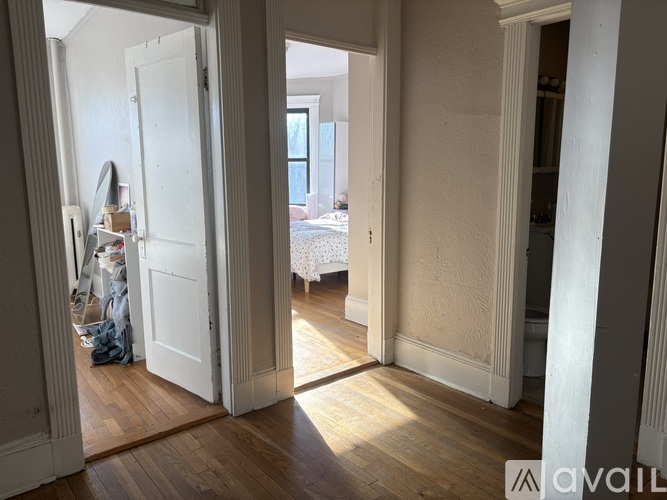 A room with a white door and a bed in the background.