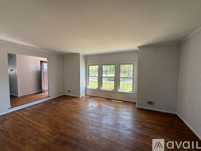 A spacious room with wooden floors and a large window.