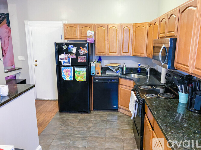 A kitchen with a black fridge and wooden cabinets.