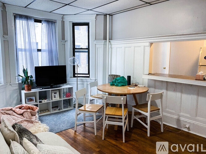 A living room with a television, a chair, a table, and a potted plant.