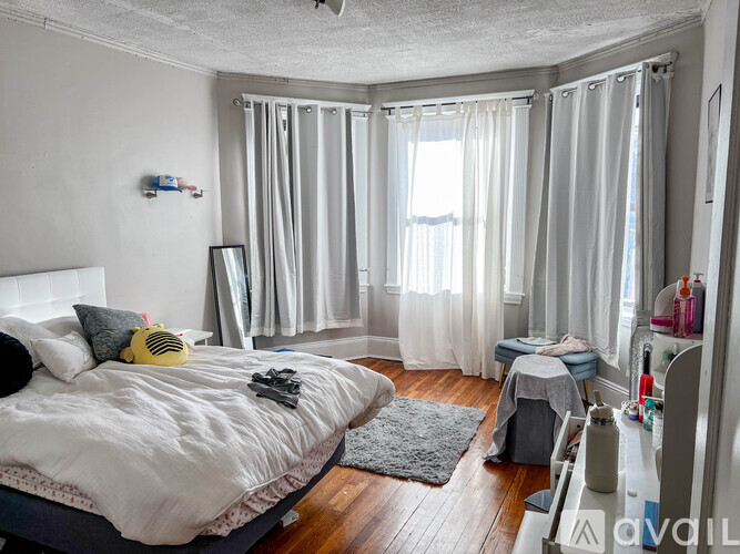 A bedroom with a large bed and a window with curtains.