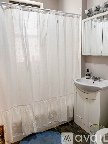 A white bathroom with a shower curtain and a white sink.