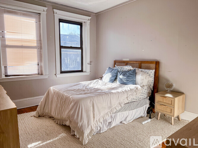 A bedroom with a bed, nightstand, and window.