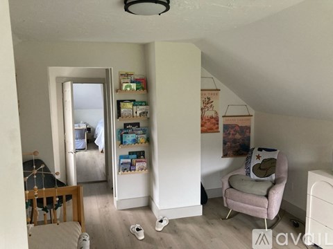 A living room with a chair, a shelf with books and a painting on the wall.