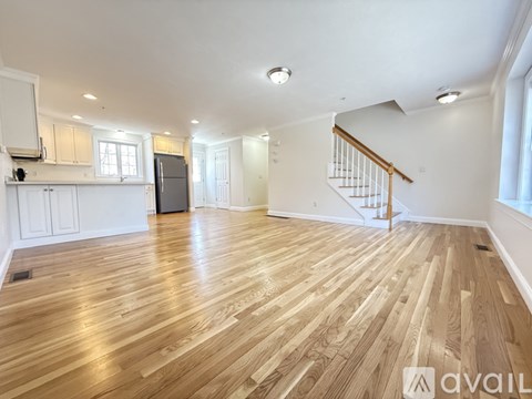 A spacious room with wooden flooring and a staircase.