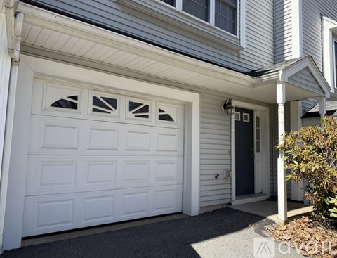 A white garage door is part of a house with a grey siding.