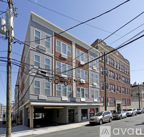 A street view of a multi-story building with a car dealership in the front.