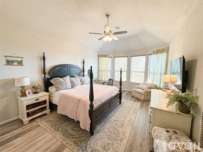 A bedroom with a large bed and a ceiling fan.