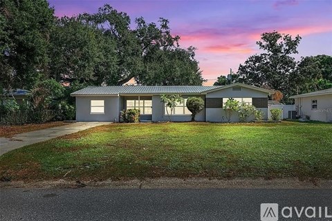 A house with a green lawn and trees in the background.