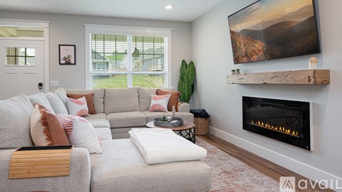 A living room with a grey couch, a fireplace, and a painting on the wall.