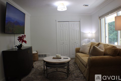 A living room with a brown couch, a coffee table, and a painting on the wall.