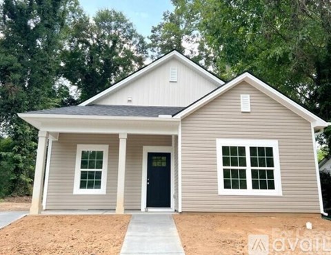 A small house with a black door and two windows is for sale.