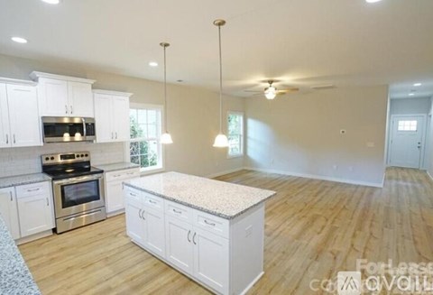 A kitchen with white cabinets and a granite countertop.