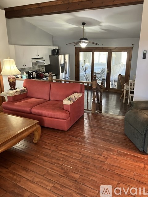 A living room with a red couch and wooden floors.