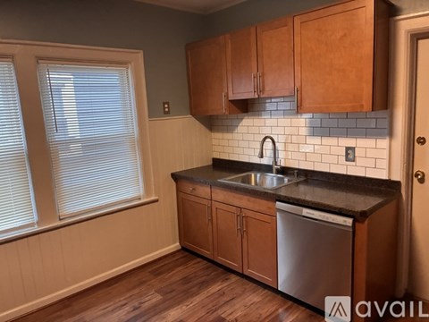 A kitchen with wooden cabinets and a stainless steel dishwasher.