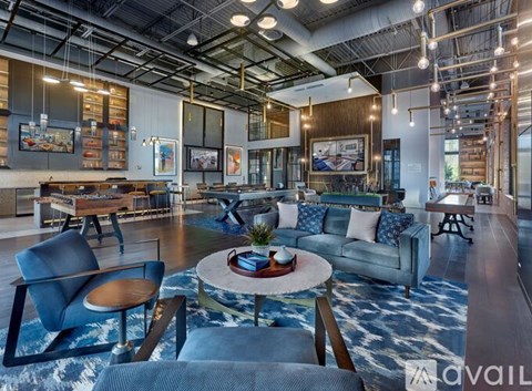 A modern living room with a blue rug and a coffee table in the center.
