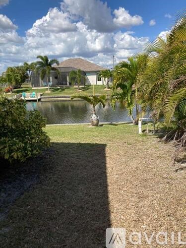 A house with a pool and palm trees in front.