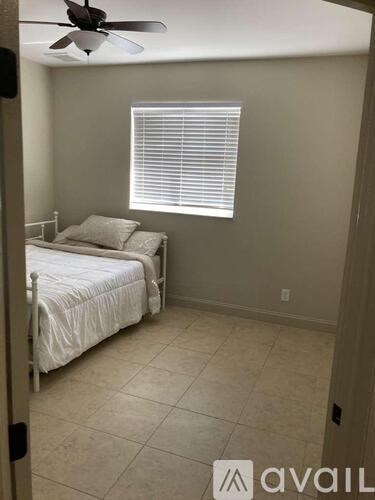 A bedroom with a bed, a window with blinds, and a ceiling fan.