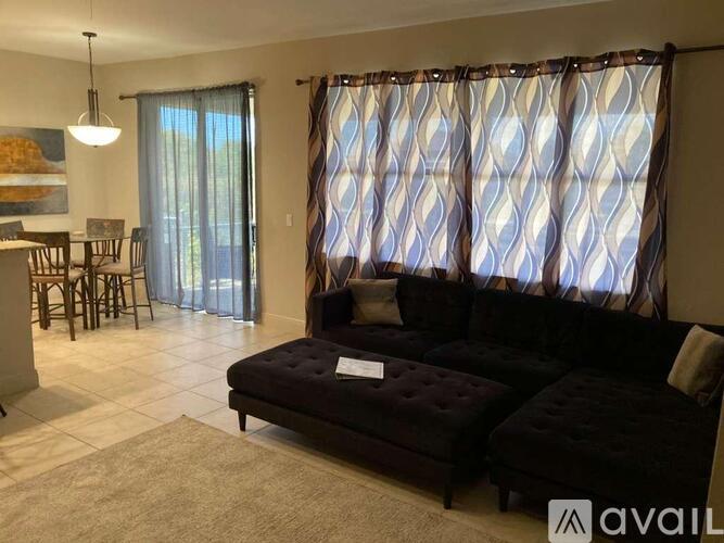 A living room with a dark sofa and a dining table.