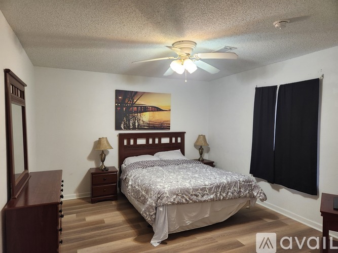 A bedroom with a bed, two lamps, and a painting on the wall.